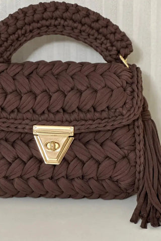Brown woven handbag with a gold clasp on a white surface