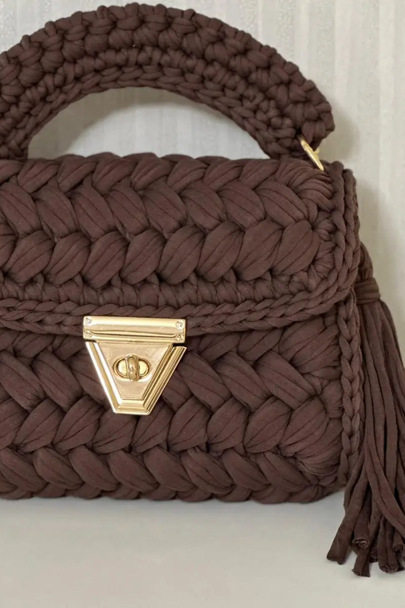 Brown woven handbag with a gold clasp on a white surface