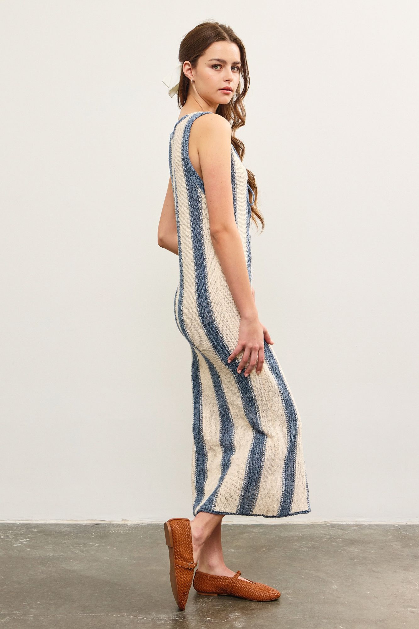 A woman standing, wearing a blue and white striped dress STMT BOUTIQUE 