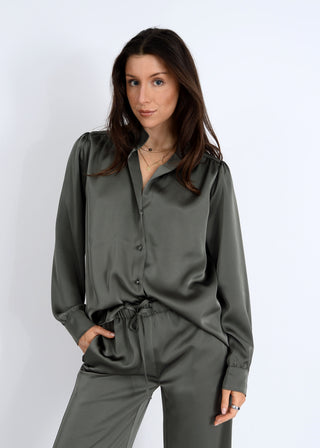 Woman wearing a green satin shirt and pants on a white background
