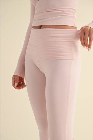 Person wearing a pink long-sleeve top and leggings on a beige background