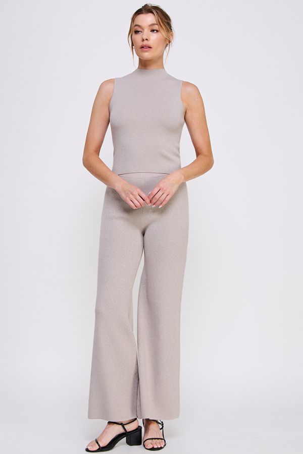 Woman wearing a beige sleeveless top and wide-leg pants on a white background