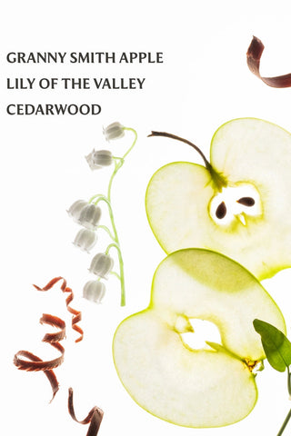 Sliced Granny Smith apple with lily of the valley and cedarwood on a white background