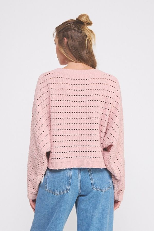 Person wearing a pink knitted sweater and blue jeans on a white background