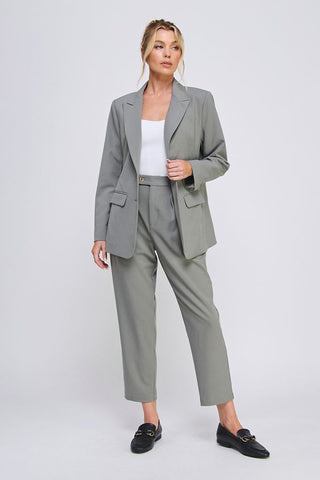 Woman wearing a gray suit with a white top on a light gray background