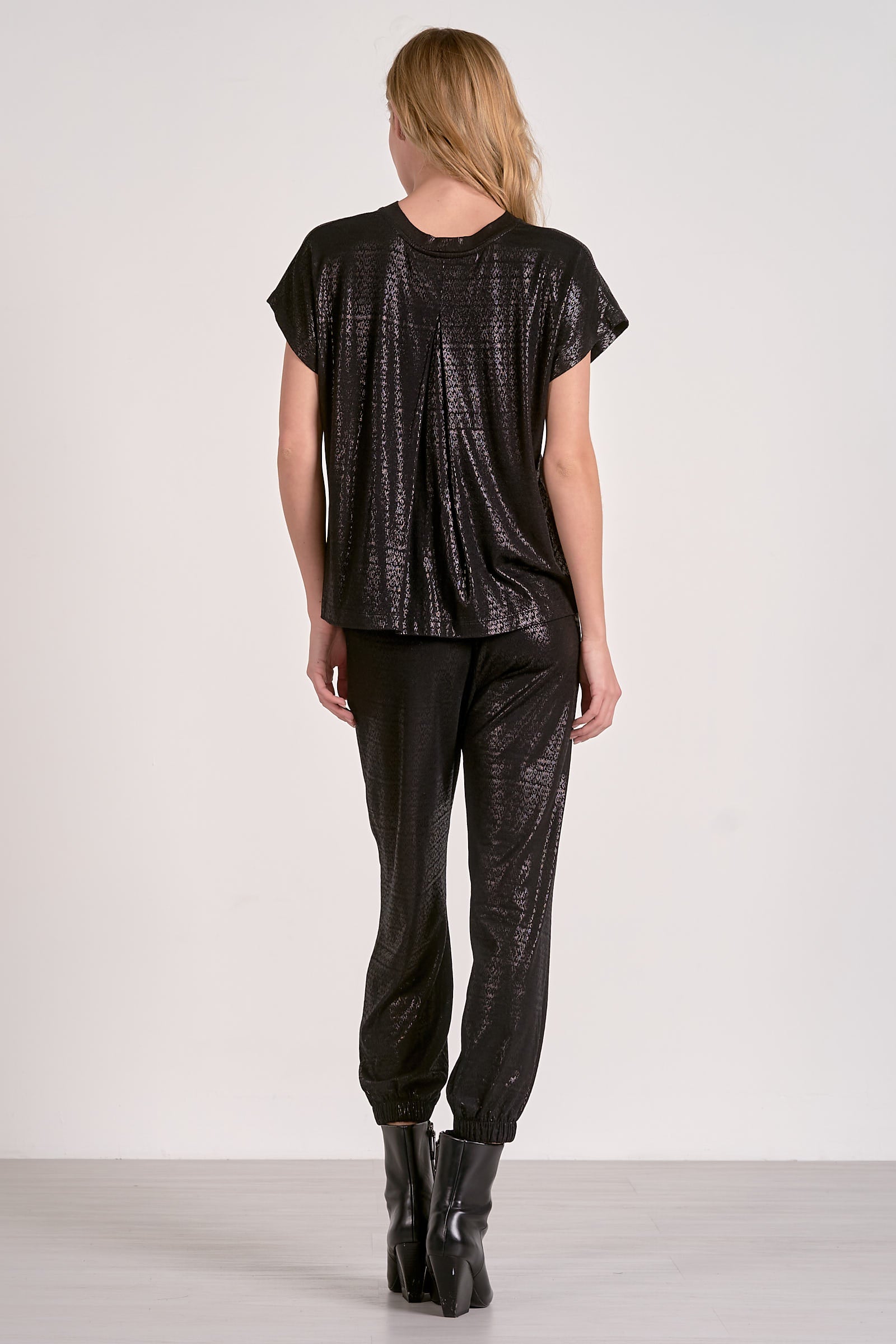 Person wearing a black patterned top and pants on a white background