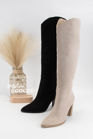 Black and beige knee-high boots on a white background with a decorative vase.