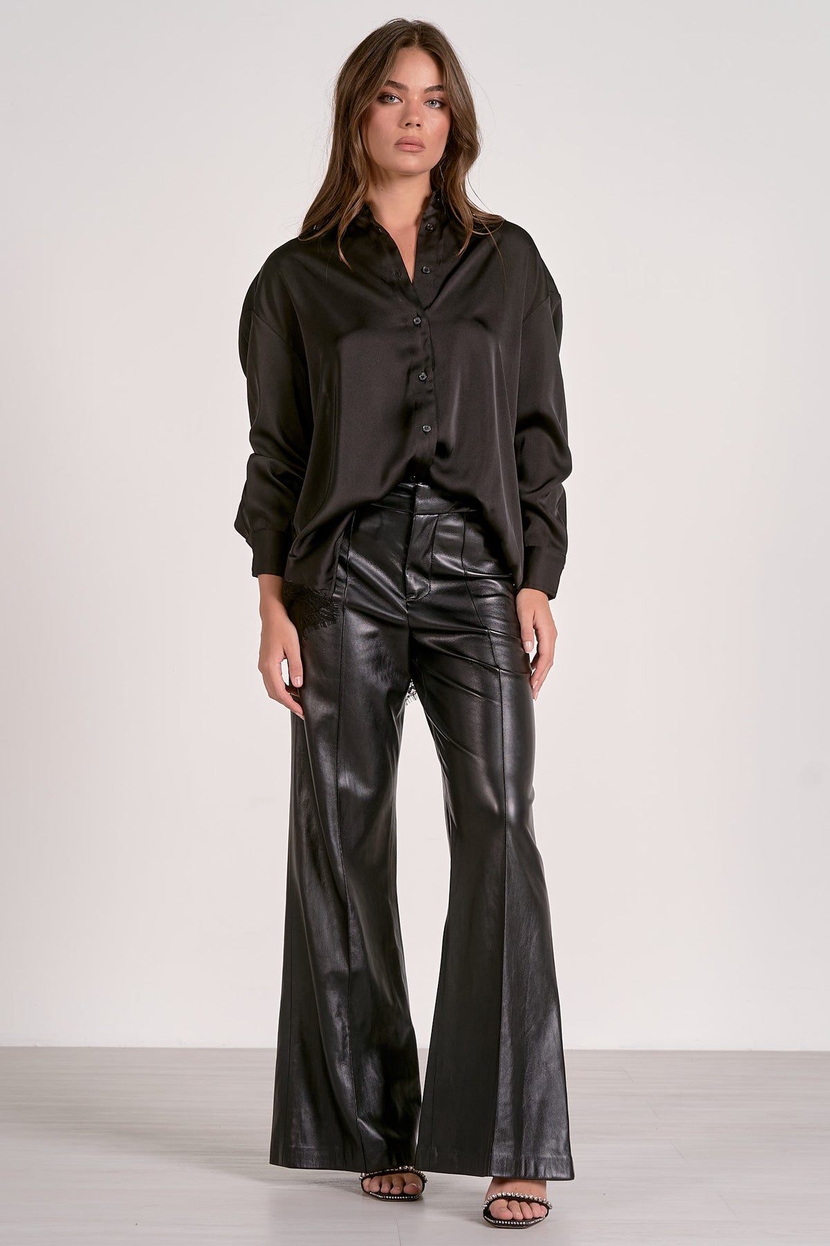 Woman wearing a black blouse and black leather pants on a white background