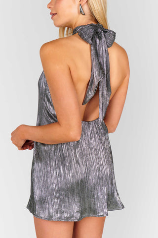 Woman wearing a gray halter romper with a tie detail on a white background