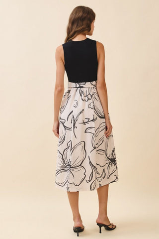 Woman wearing a black top and white floral skirt on a beige background