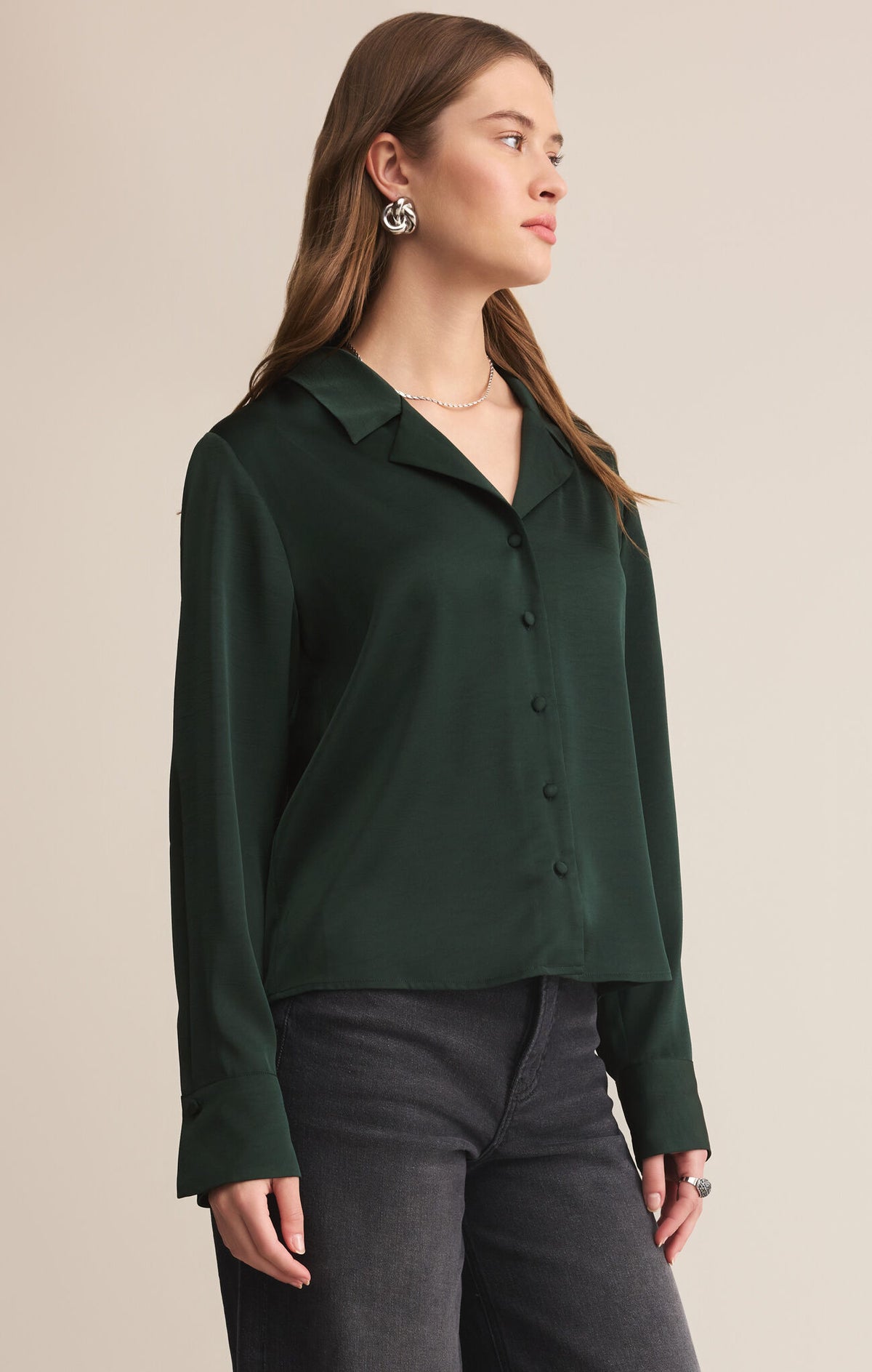 Woman wearing a dark green shirt against a beige background