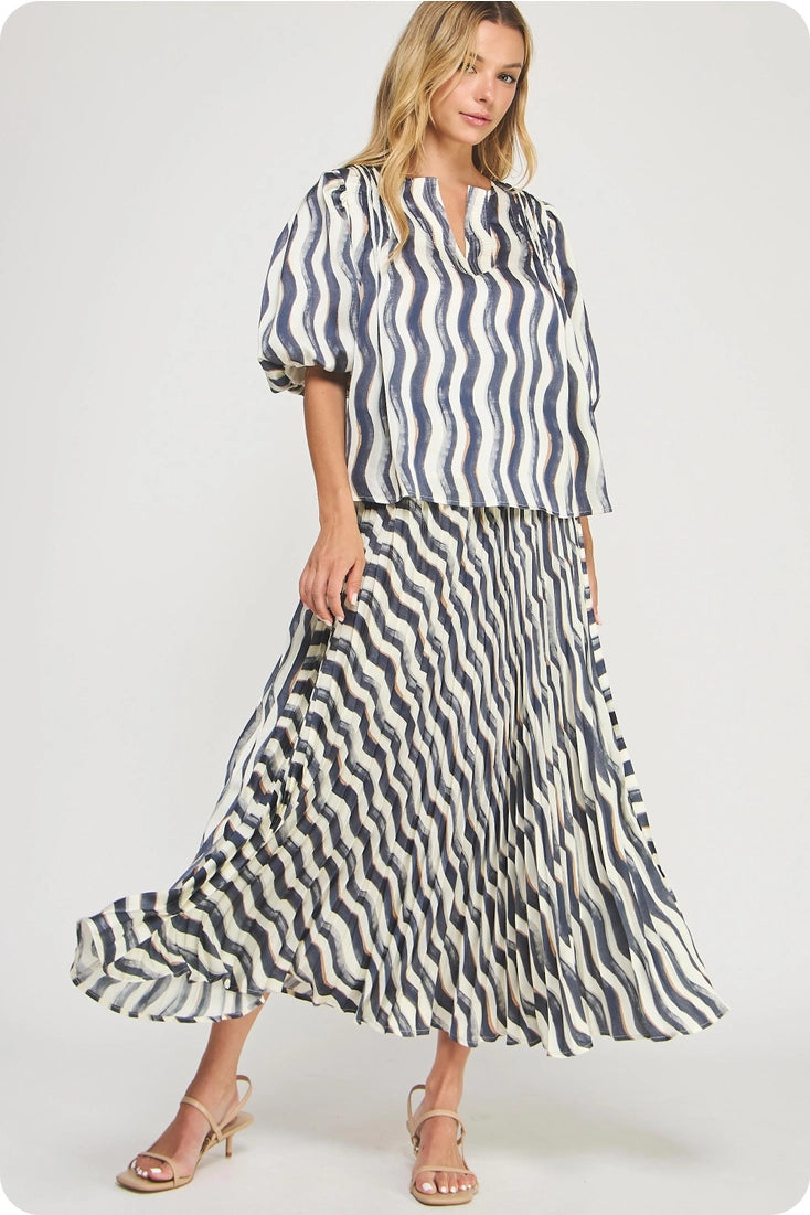 Woman wearing a blue and white striped blouse and a long black and white patterned skirt on a white background