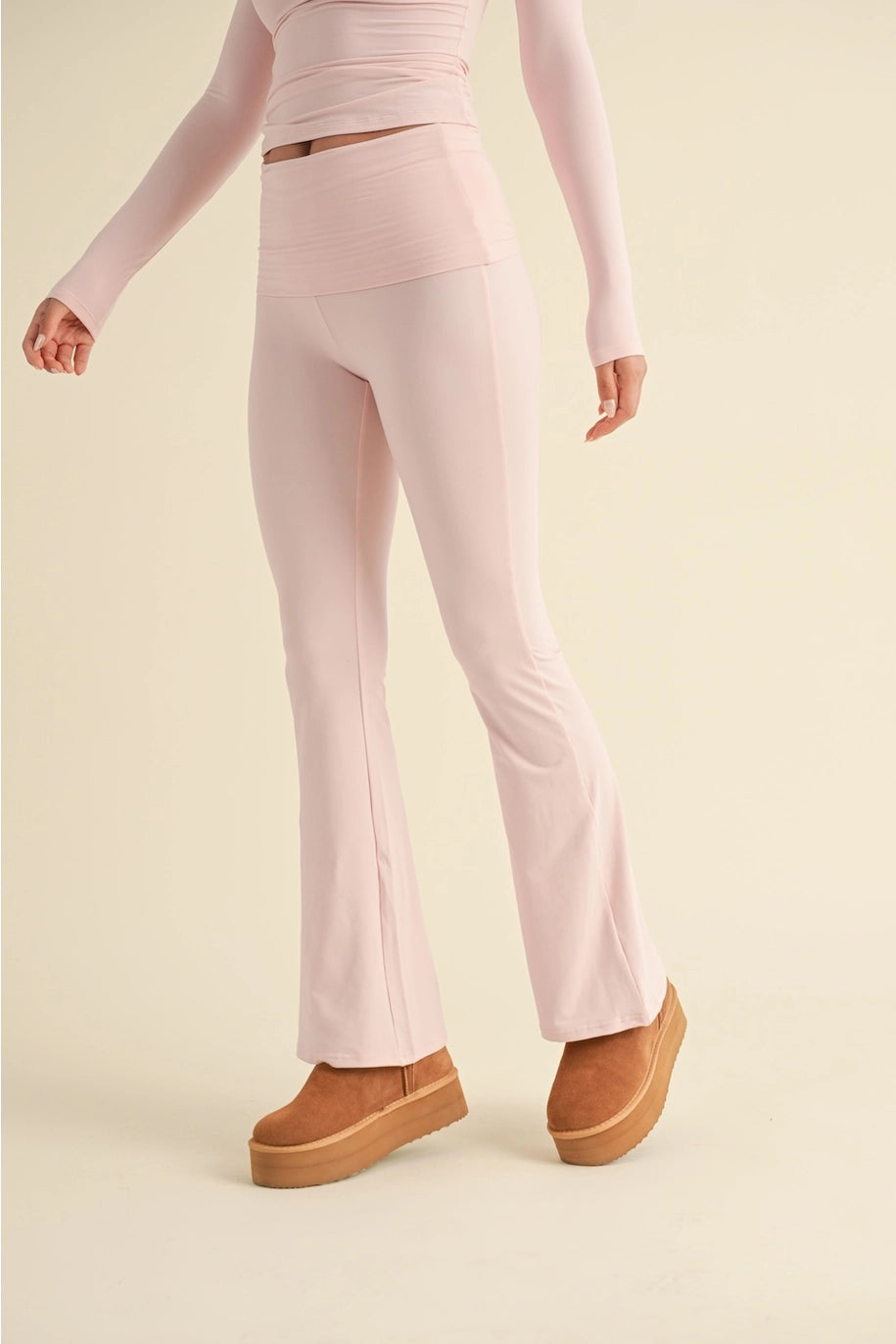 Person wearing a pink outfit with flared pants on a beige background