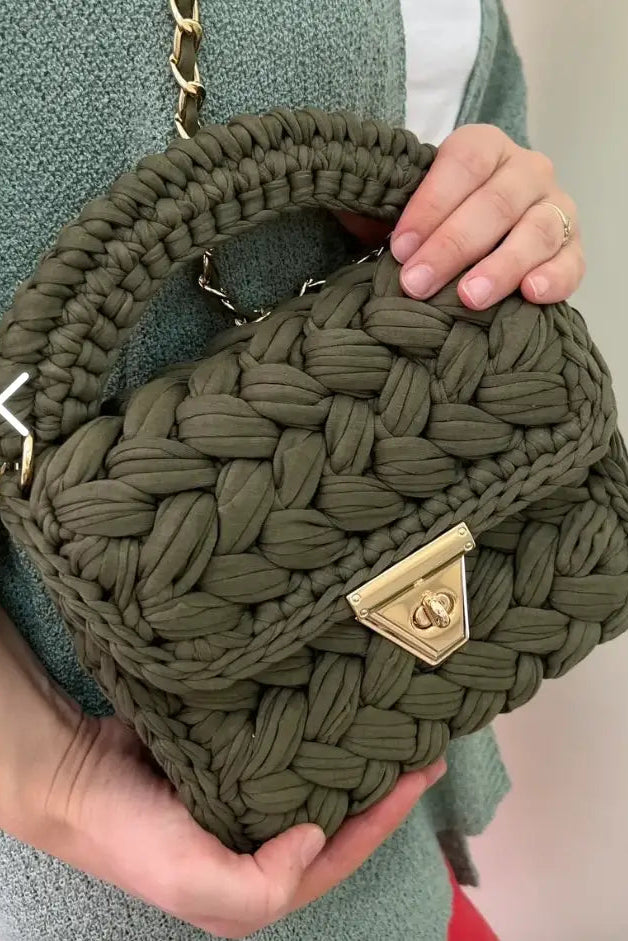 Green woven handbag held by a person with a blurred background