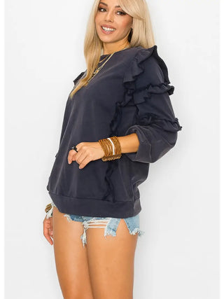 Woman wearing a navy blue ruffled top and denim shorts on a white background