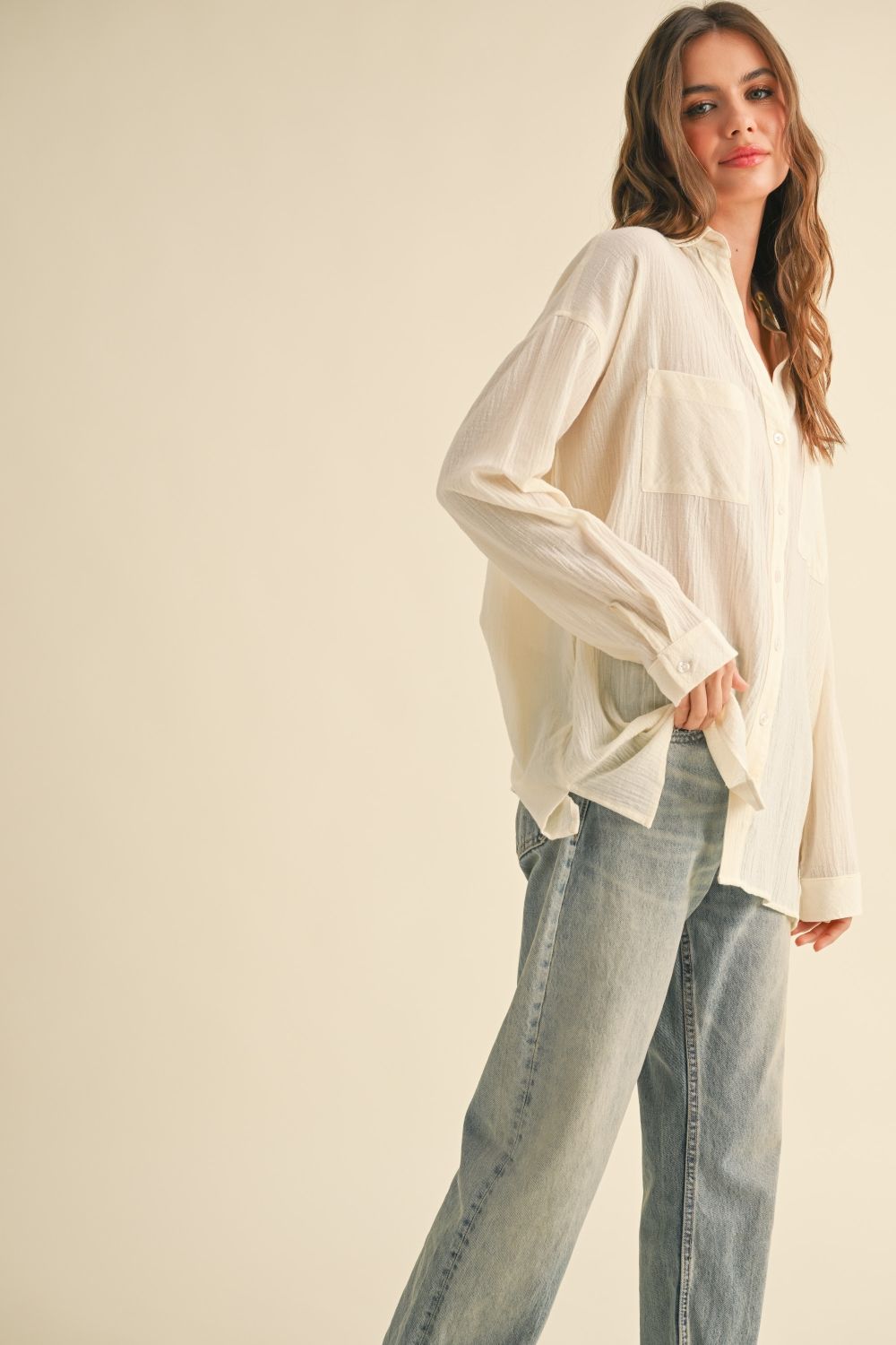 Woman wearing a white blouse and blue jeans on a beige background
