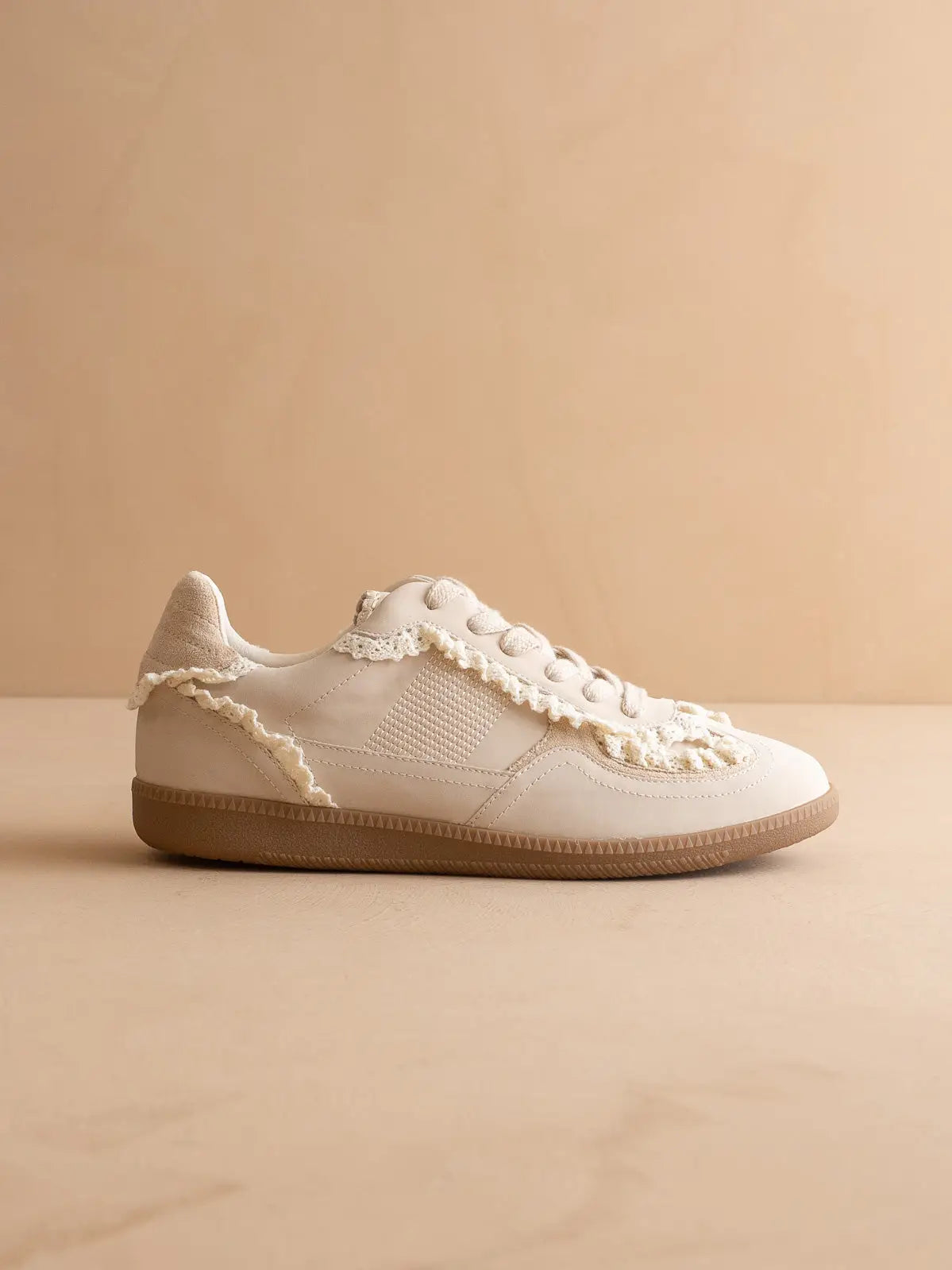 White sneaker with lace details on a beige background
