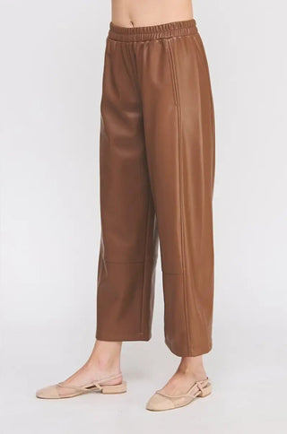 Brown leather pants worn by a person on a white background