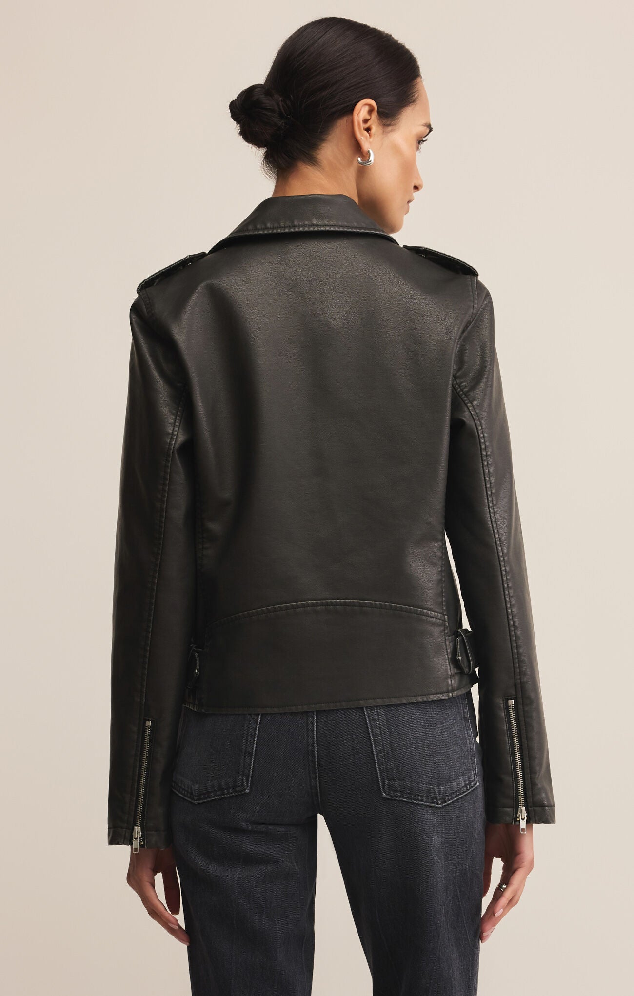 Woman wearing a black leather jacket on a beige background