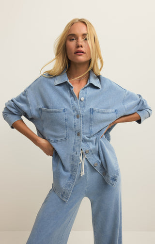 Woman wearing a denim jumpsuit against a plain background