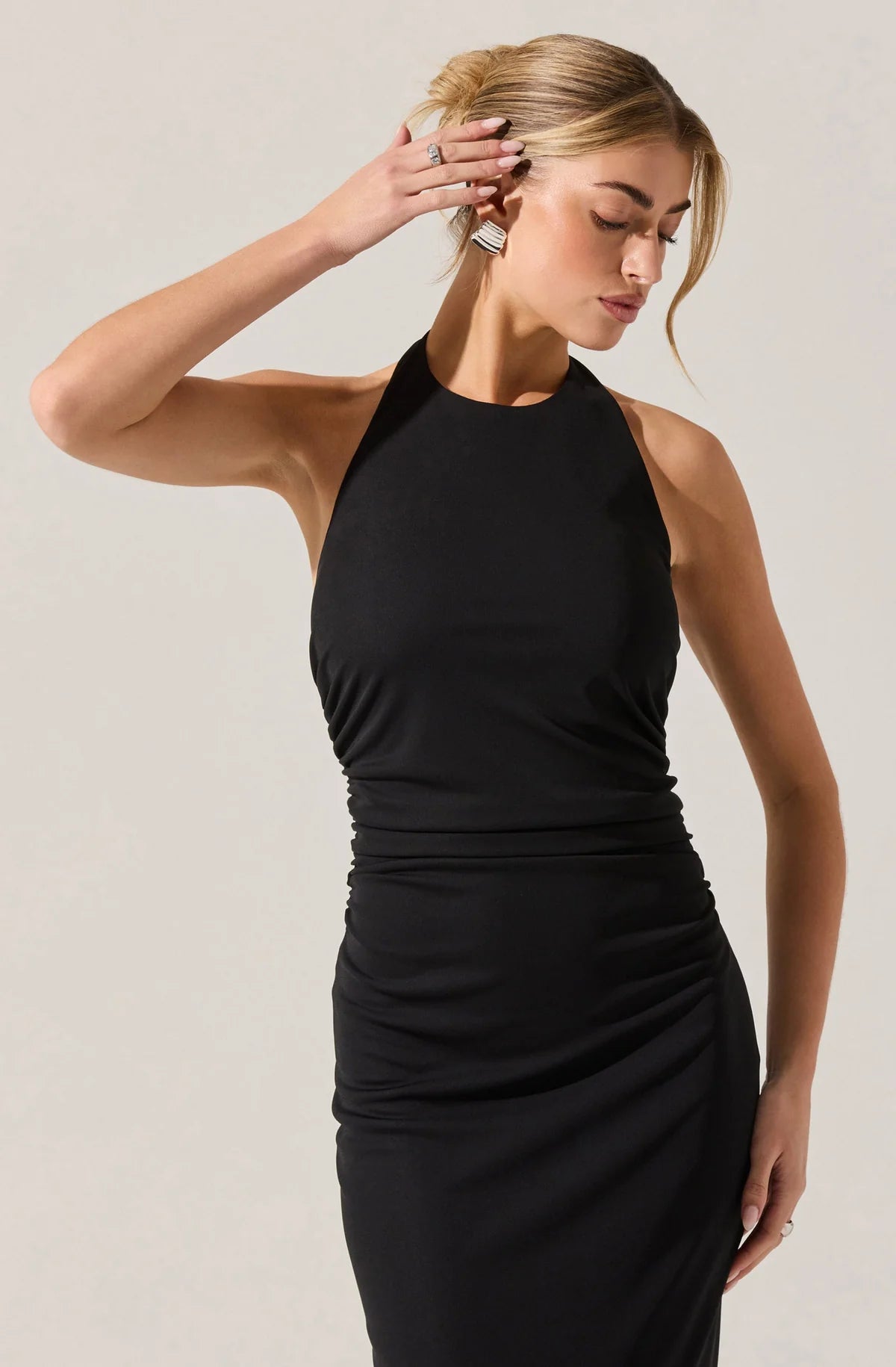 Woman wearing a black halter neck dress against a plain background