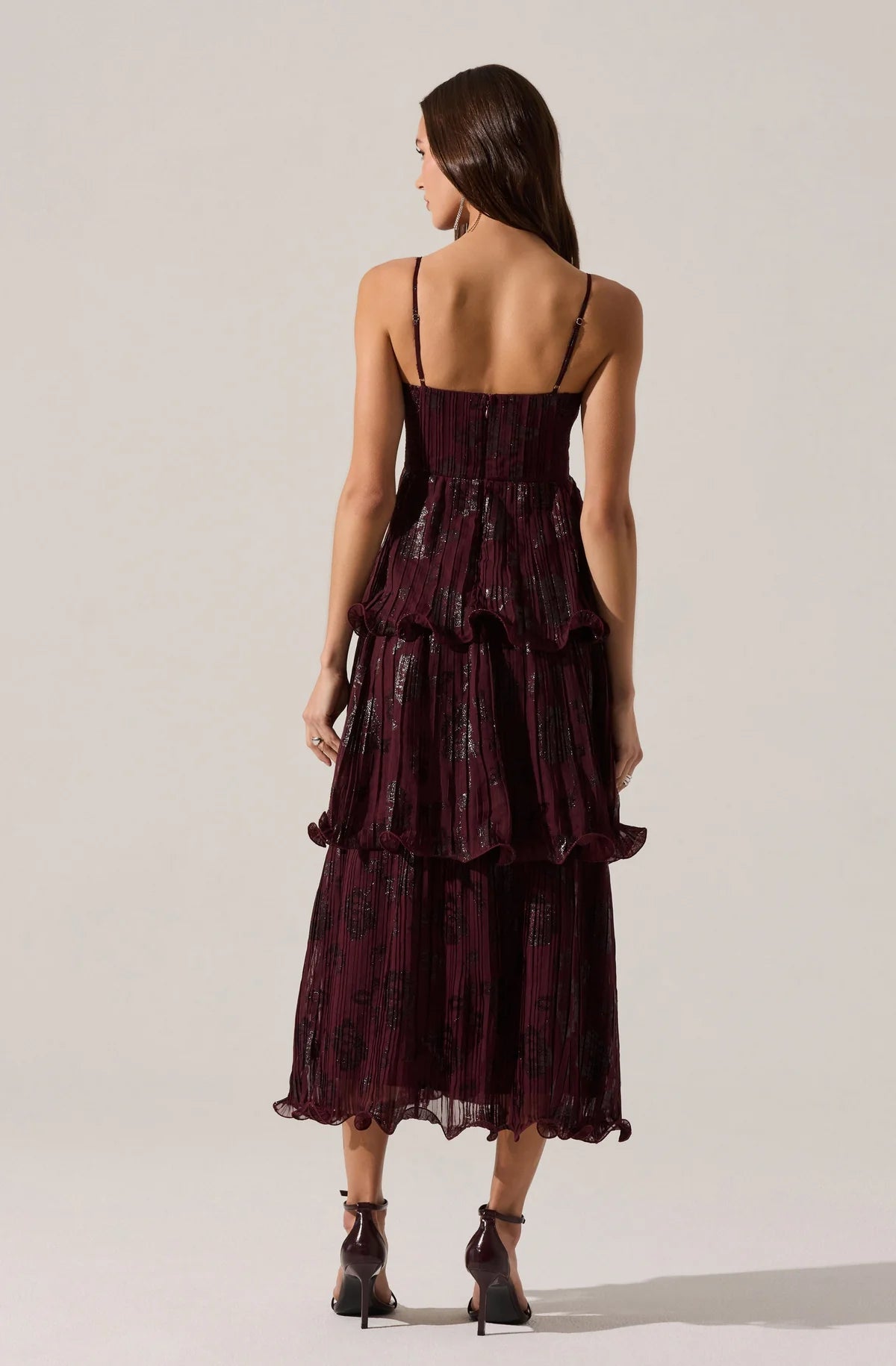 Woman wearing a burgundy ruffled dress on a white background