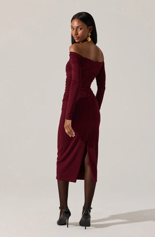 Woman wearing a burgundy off-shoulder dress on a plain background