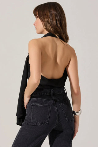 Woman wearing a black halter top and high-waisted jeans against a plain background