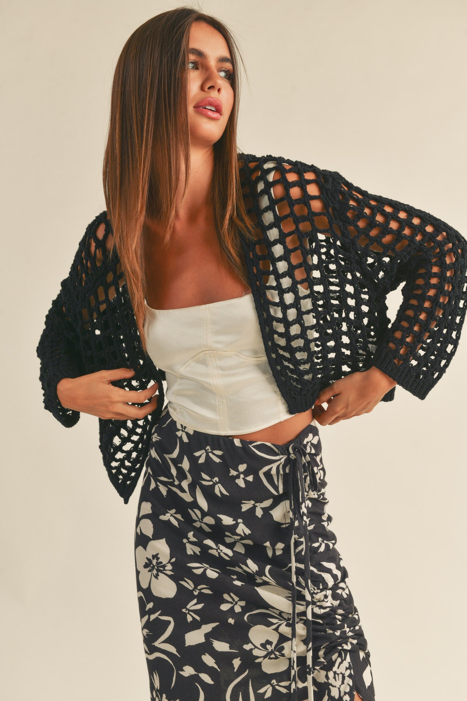 A female model wearing a beige crochet knit crop cardigan 