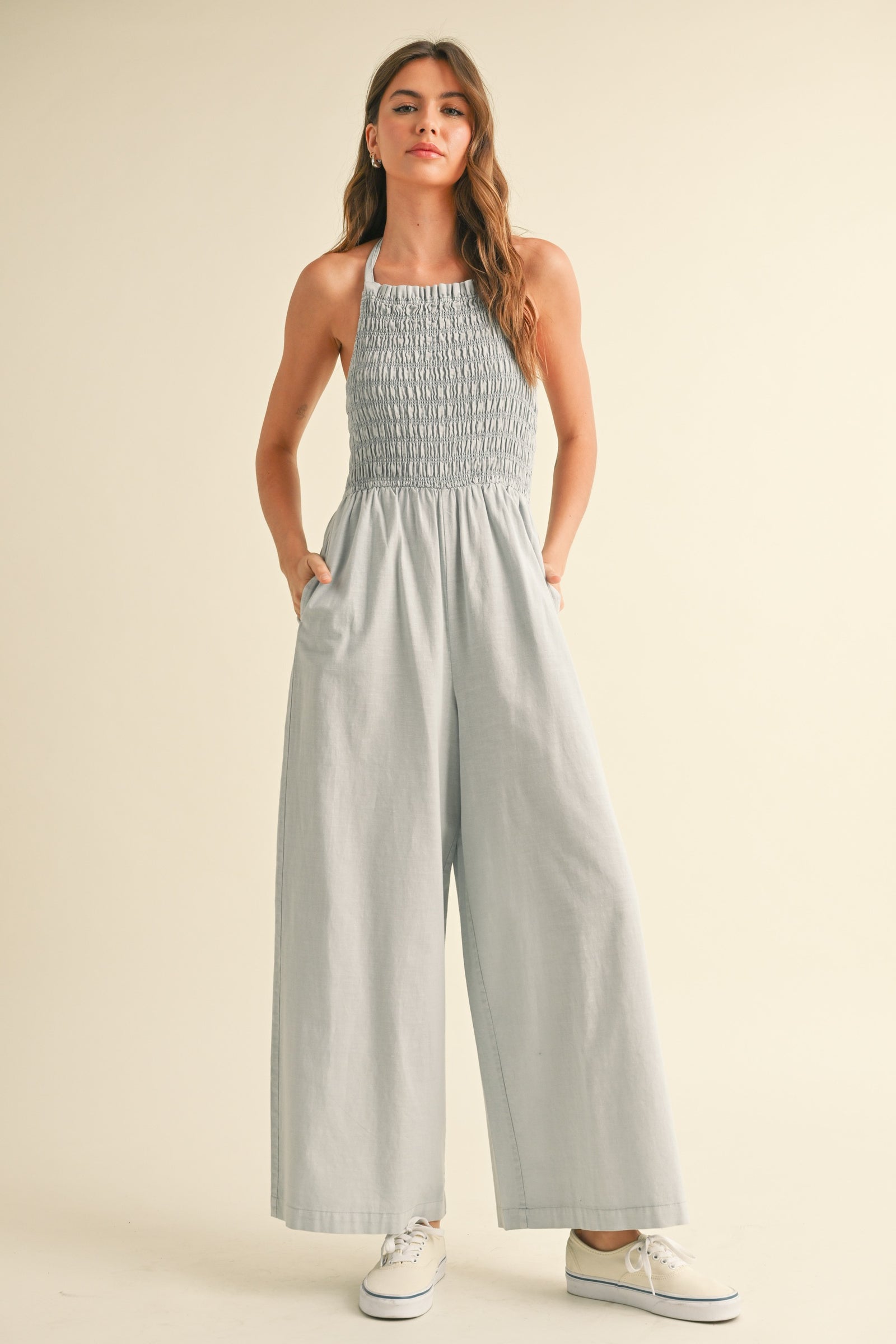 A woman wearing a gray halter jumpsuit with a smocked bodice STMT BOUTIQUE 