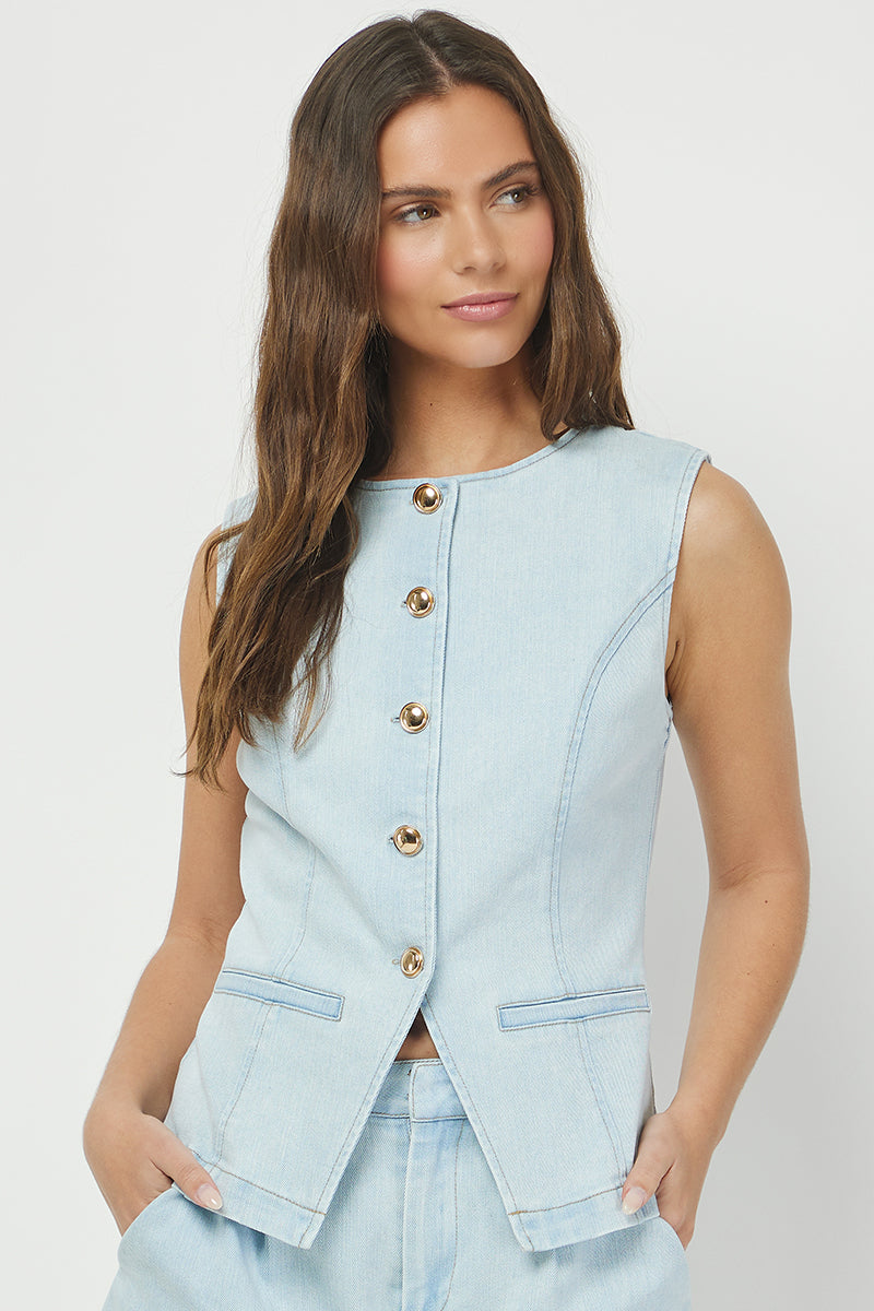 A woman wearing a light blue denim button vest with front pockets STMT BOUTIQUE 