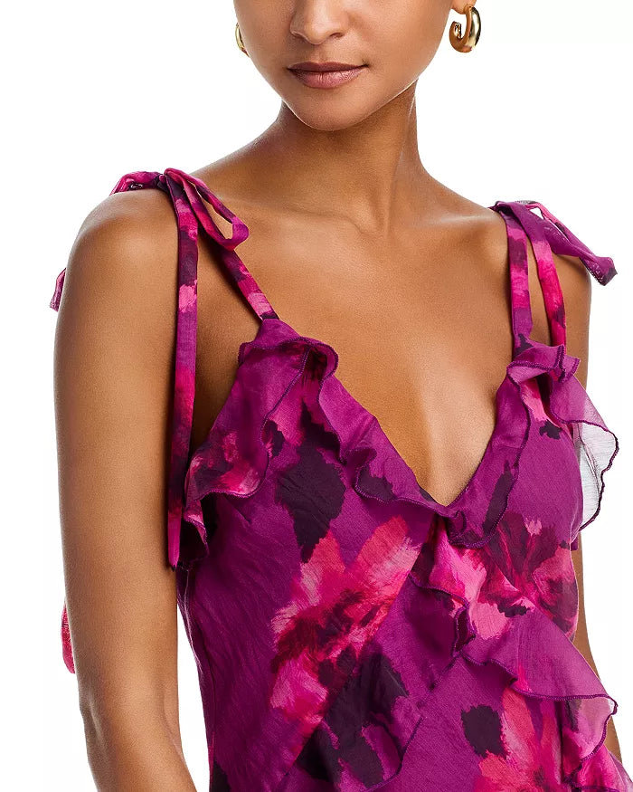 Close-up of a woman wearing a vibrant pink floral dress with ruffled straps on a white background.