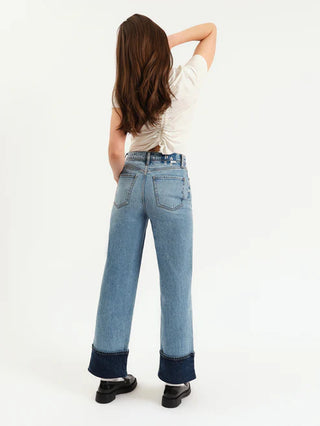 Person wearing light blue jeans with dark cuffs on a white background