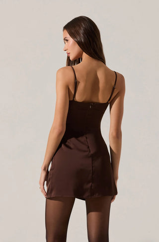 Woman wearing a brown dress with thin straps on a plain background
