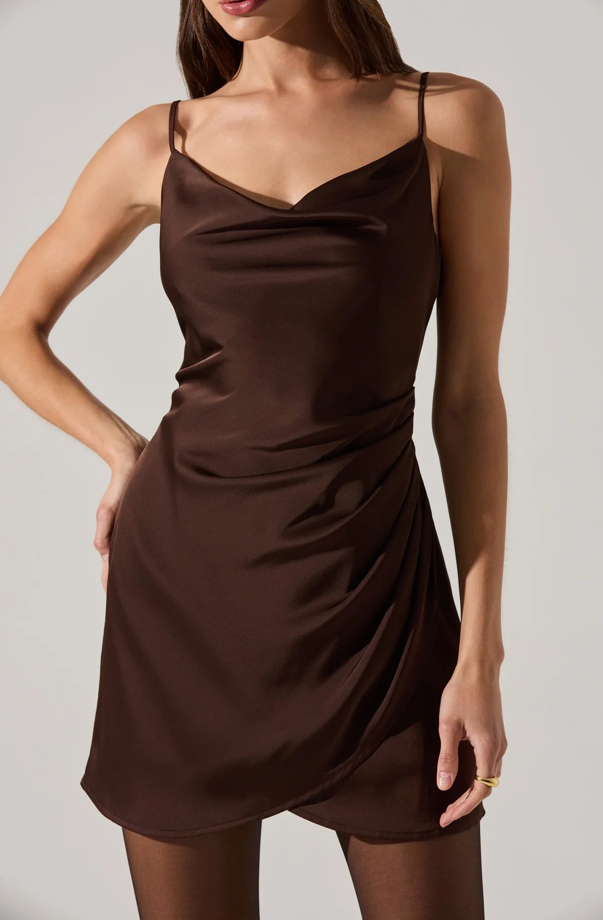 Woman wearing a brown slip dress against a plain background
