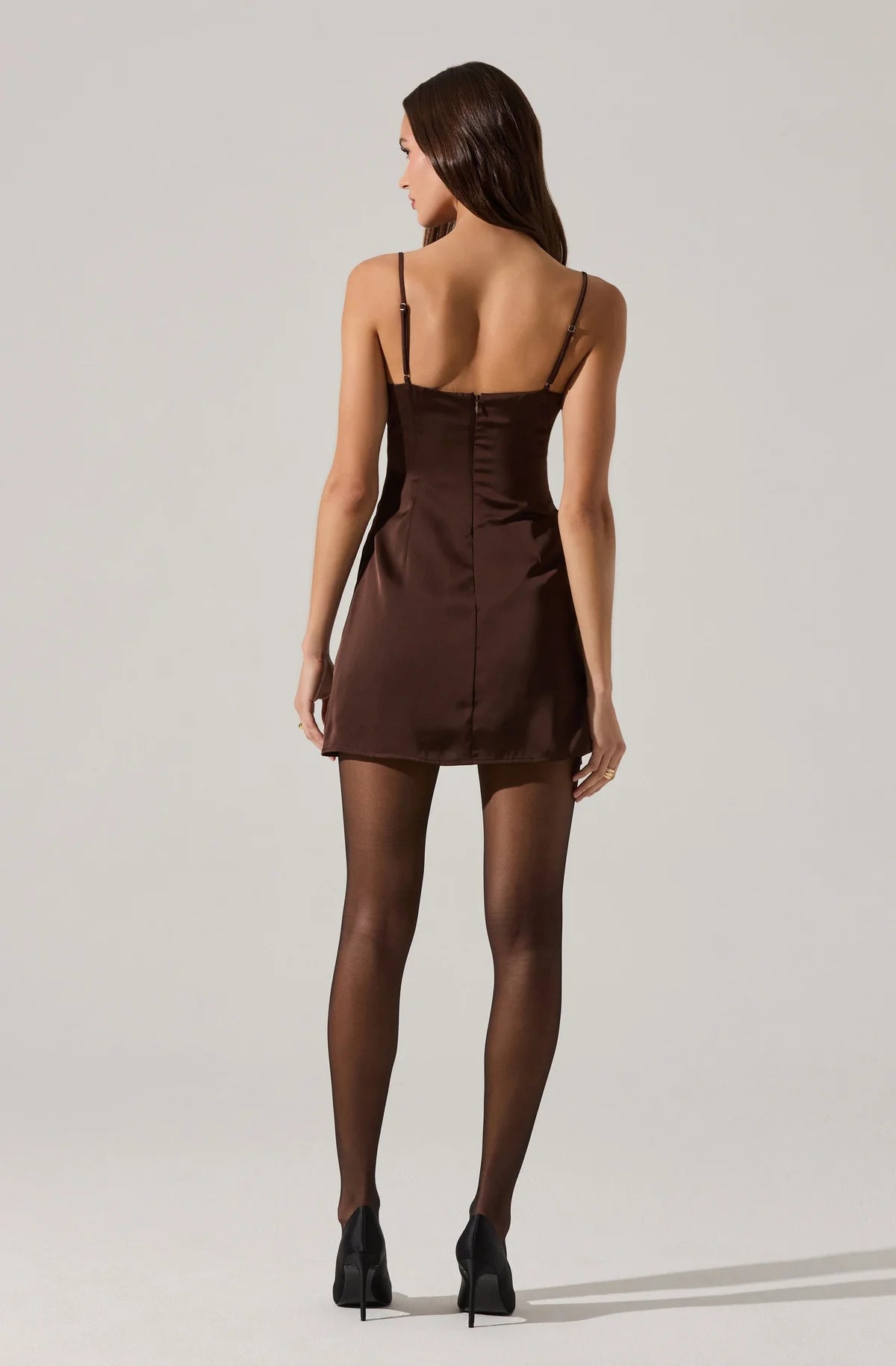 Woman wearing a brown satin slip dress on a plain background