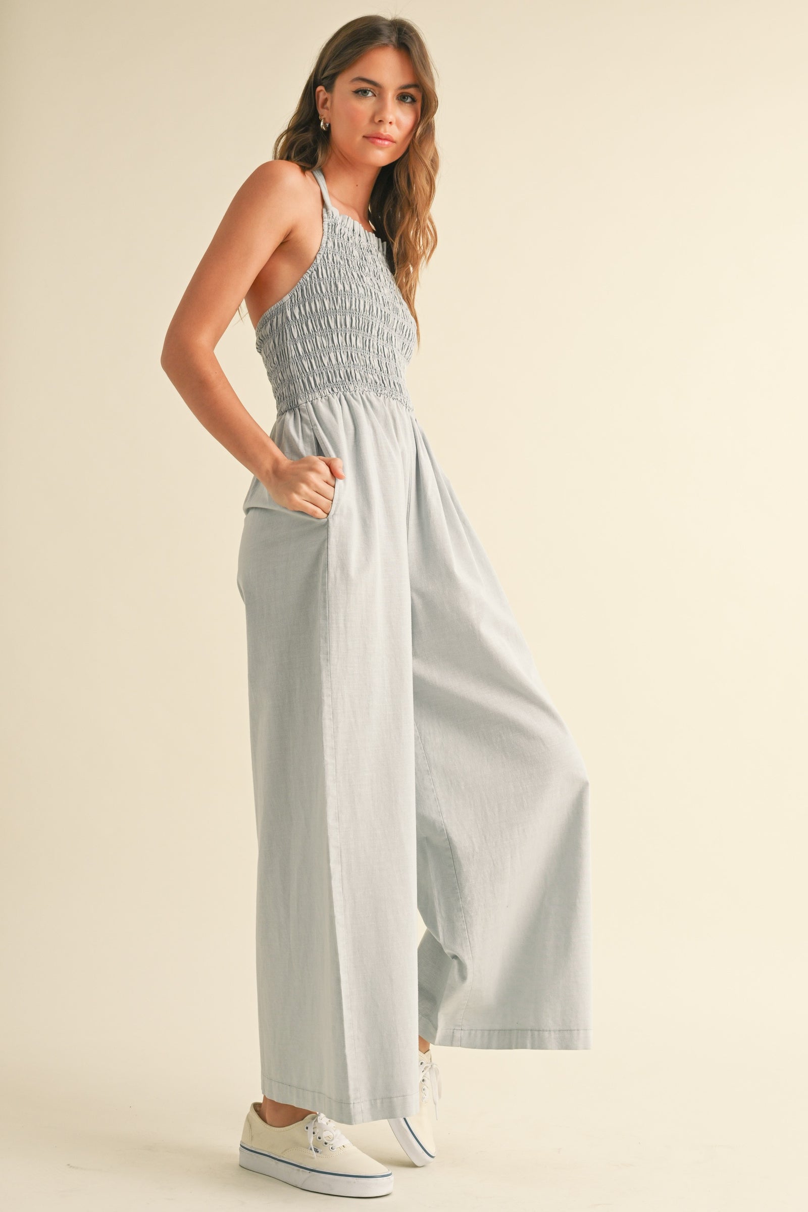 A woman wearing a gray halter jumpsuit with a smocked bodice STMT BOUTIQUE 
