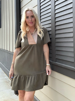 Woman wearing a green dress standing against a building exterior.