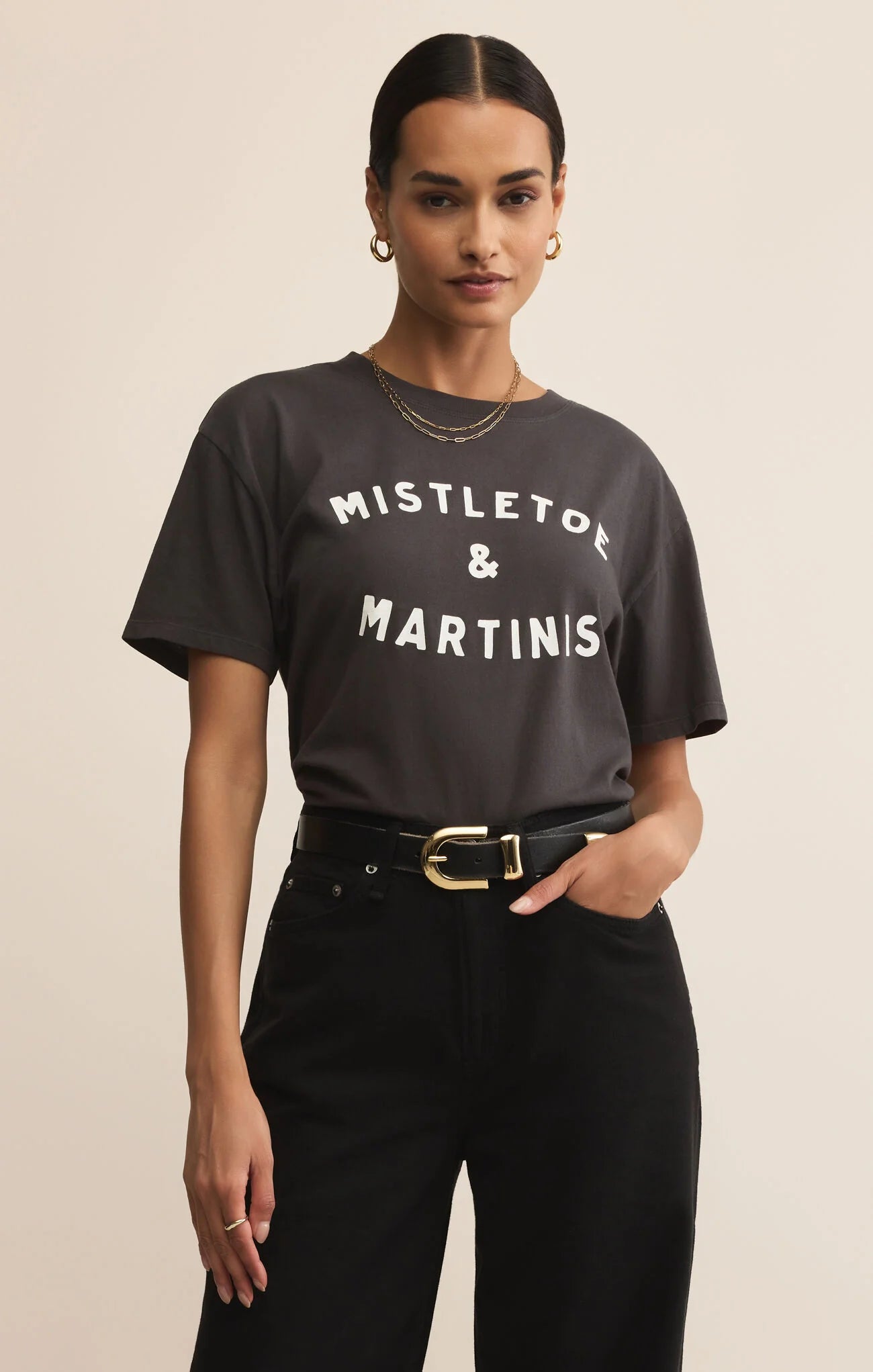 Woman wearing a black t-shirt with 'Mistletoe & Martinis' text on a beige background