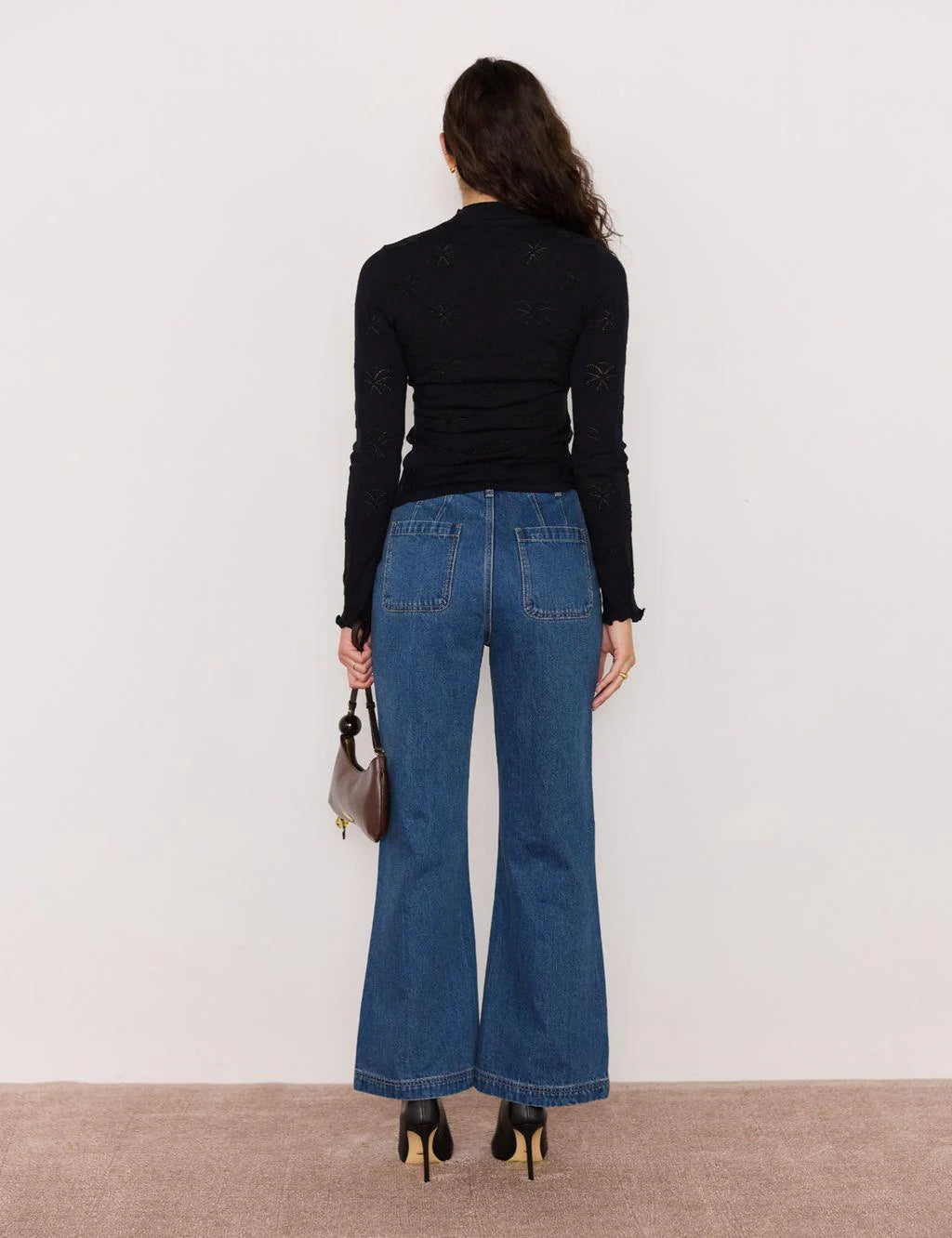 Person wearing blue jeans and a black top against a white background
