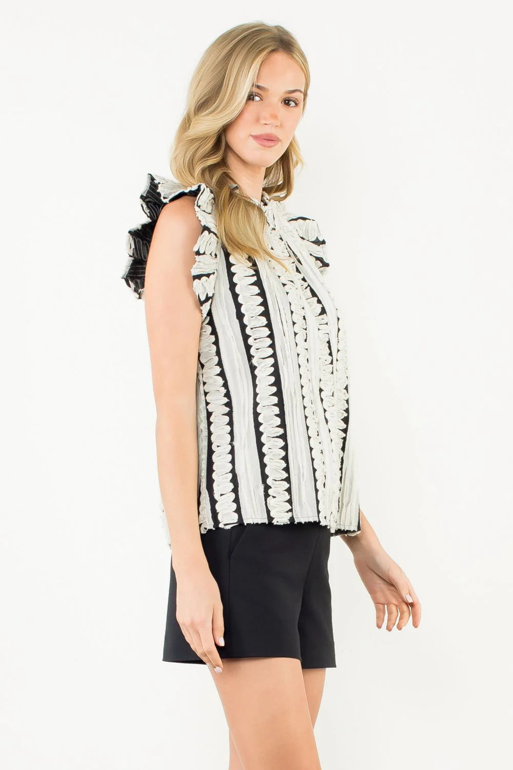 Woman wearing a black and white patterned top with black shorts on a white background