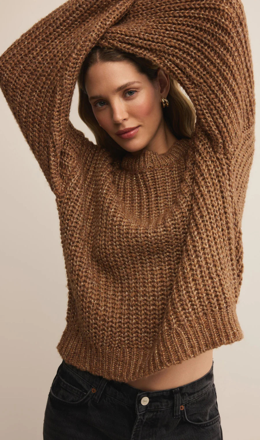 Woman wearing a brown knitted sweater against a beige background