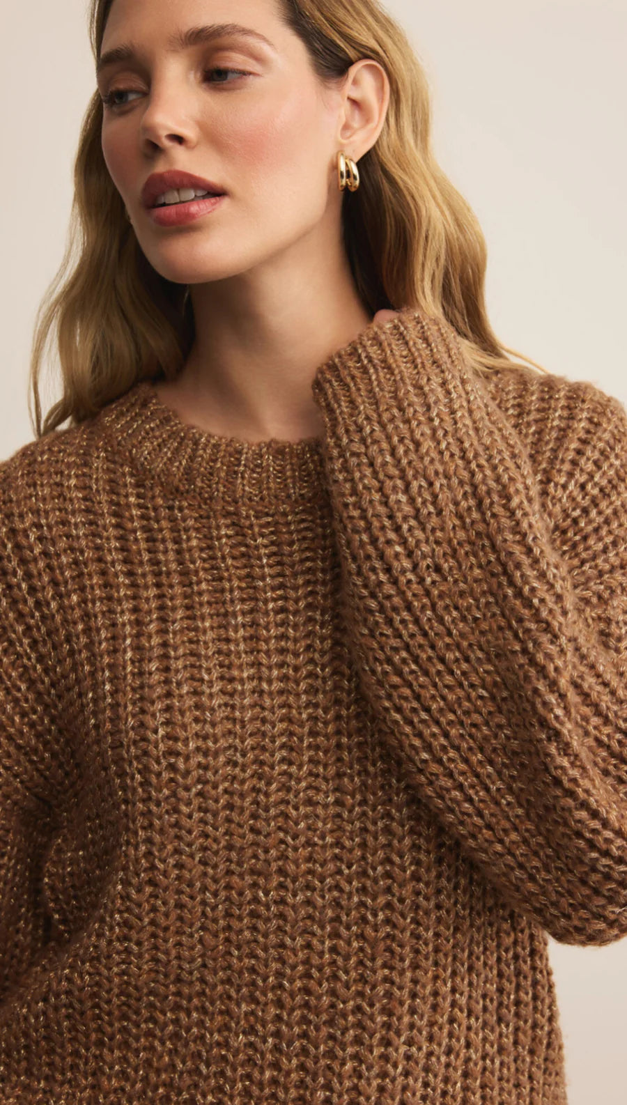 Woman wearing a brown knitted sweater against a neutral background