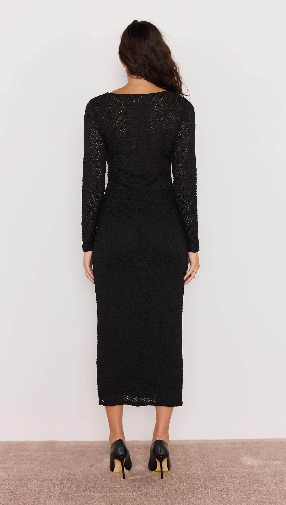 Woman wearing a black dress with long sleeves against a white background