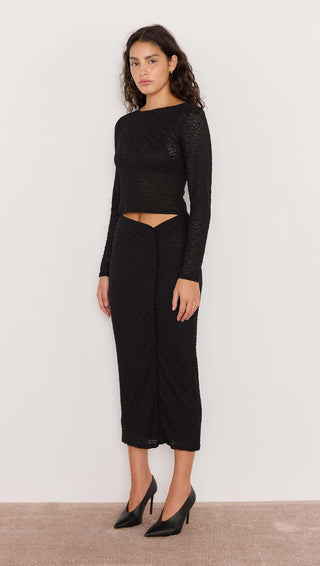 Woman wearing a black lace outfit on a plain background