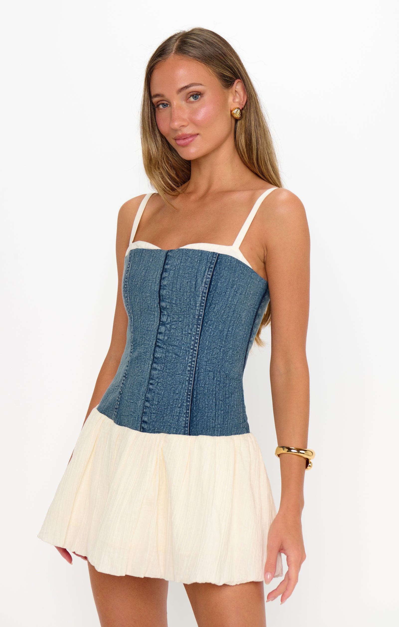 Woman wearing a denim and cream dress on a white background