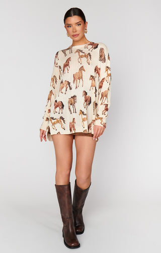 Woman wearing a patterned dress with horse designs and brown knee-high boots on a white background
