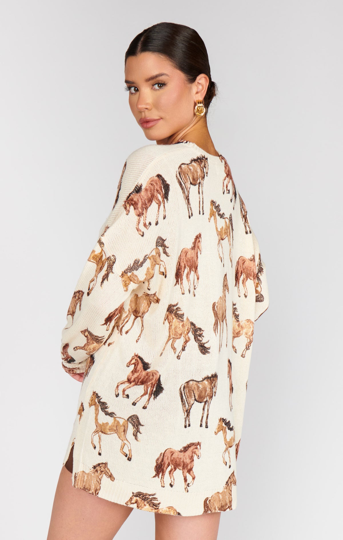 Woman wearing a cream dress with horse print on a plain background