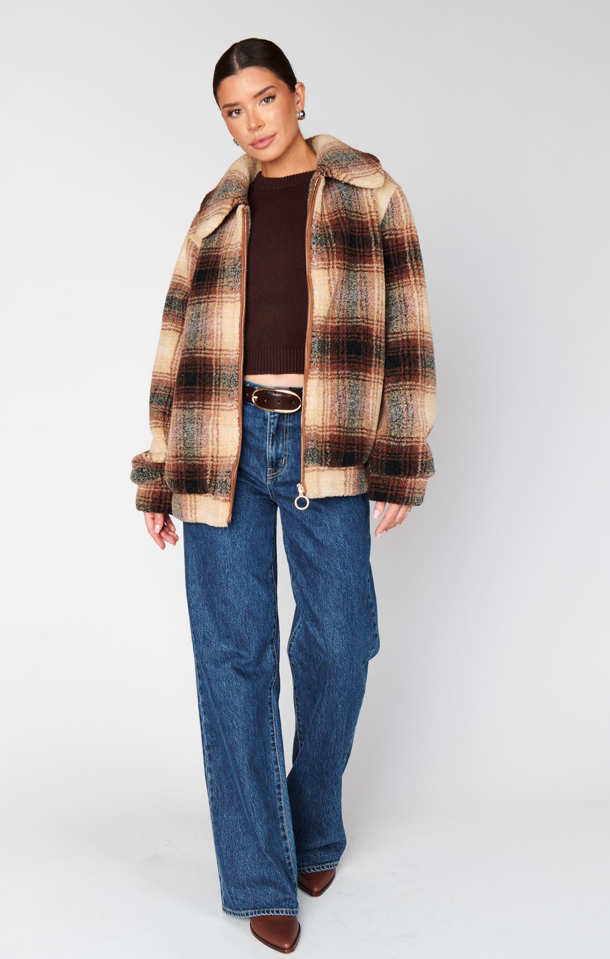 Woman wearing a plaid jacket and blue jeans on a white background