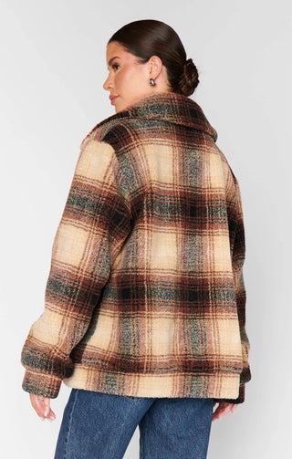 Person wearing a plaid jacket with a neutral background